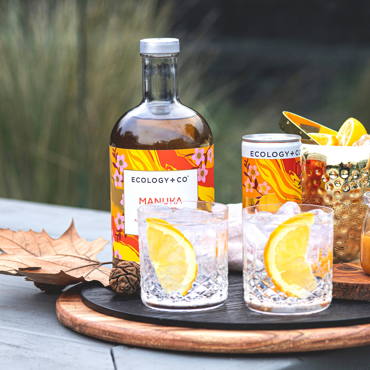 Ecology & Co Manuka Botanical Blend bottle and ready-to-drink Manuka Spritz can on garden table